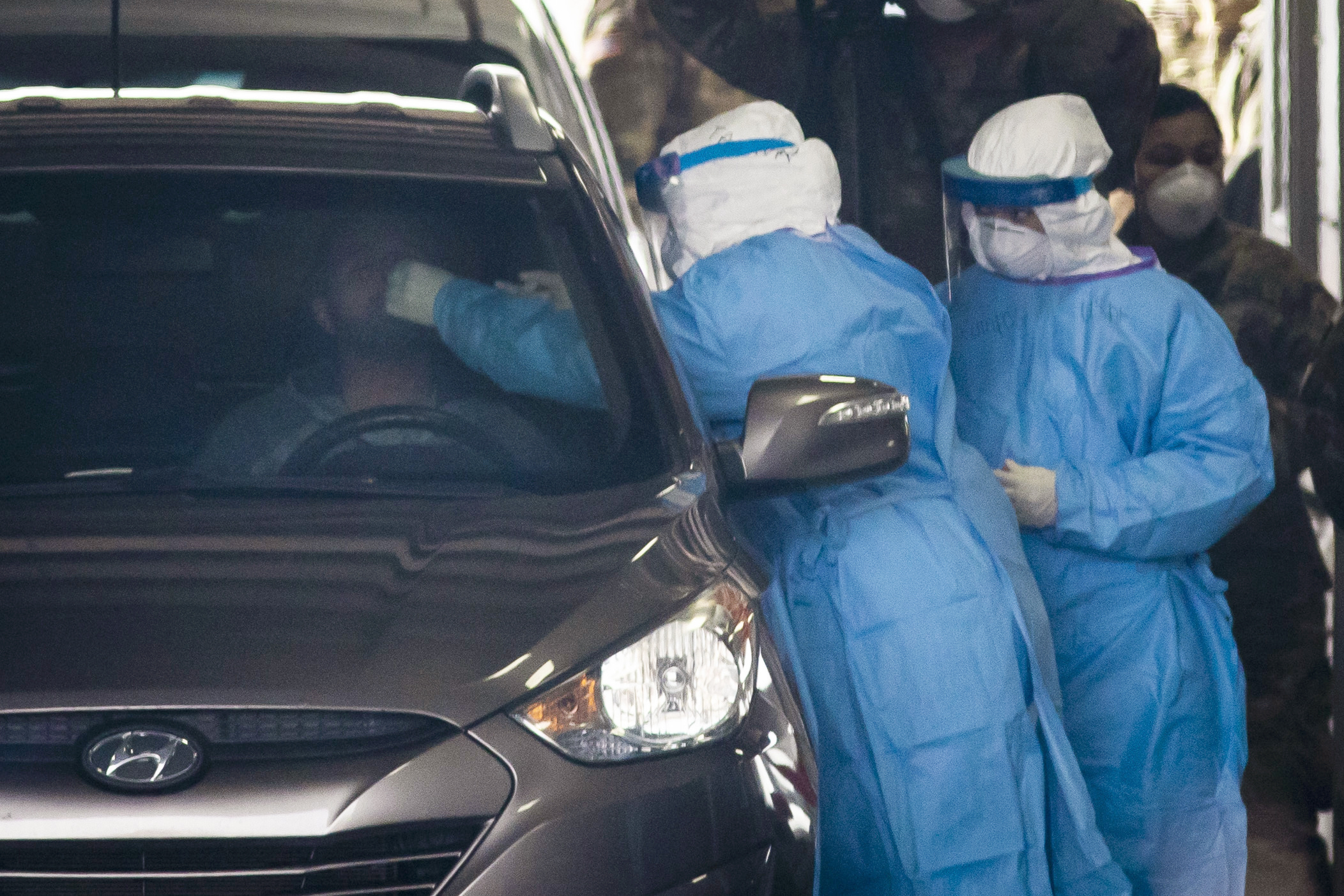  Workers test a man for coronavirus at a drive-through clinic in Illinois
